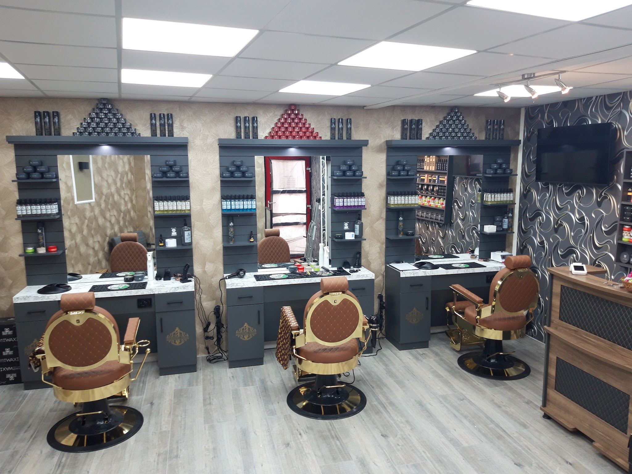 De zaak van Barbershop Jwan: drie werkplekken met spiegels en drie bruine kappersstoelen met gouden frame