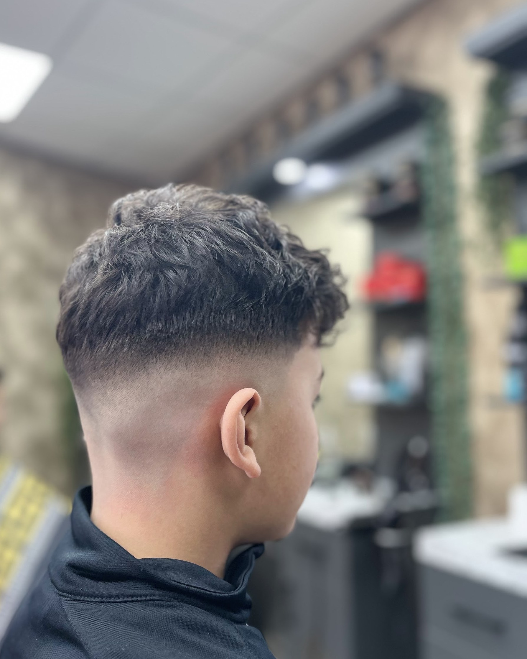 Jonge klant met een mid fade en krullend haar bovenop, in de zaak